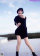 A woman in a black dress and boots posing for a picture.