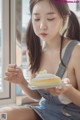 A woman sitting on a window sill eating a piece of cake.