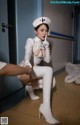 A woman in a white nurse outfit is sitting on the floor.