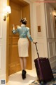 A woman standing in front of a door with a suitcase.