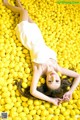 A woman laying on top of a pile of lemons.