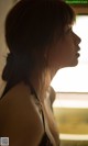 A woman in a black bra looking out a window.