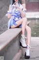 A woman in a blue and white outfit sitting on a ledge.