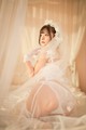 A woman in a wedding dress sitting on a bed.