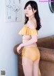 a woman in a yellow bikini standing next to a couch