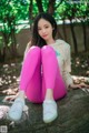 A woman sitting on a rock in a park.