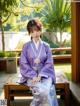 A woman in a purple hanbok sitting on a wooden bench.