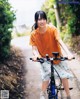 A young woman riding a bike down a dirt road.