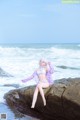 A woman sitting on a rock by the ocean.